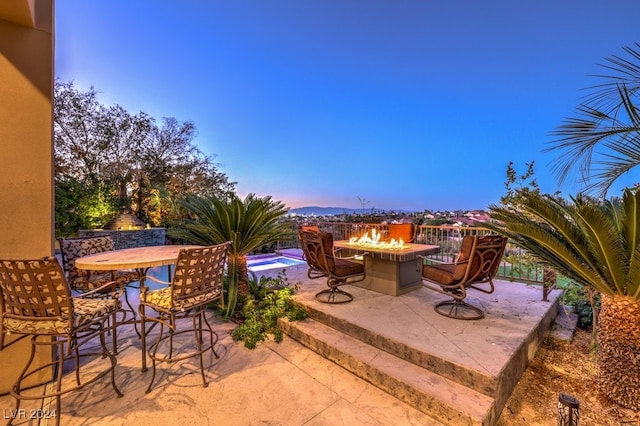 patio terrace at dusk featuring a pool and an outdoor fire pit