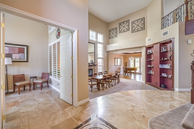 foyer entrance featuring a fireplace, a towering ceiling, and a chandelier