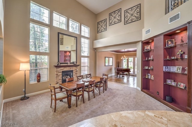 dining area with a stone fireplace, a towering ceiling, and a wealth of natural light