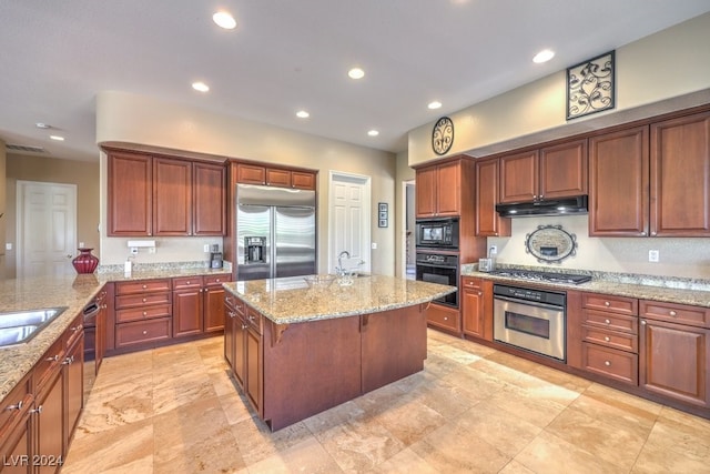 kitchen featuring black appliances, light stone countertops, a center island, sink, and a breakfast bar area