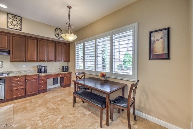 kitchen with light stone countertops, built in desk, oven, decorative light fixtures, and range hood