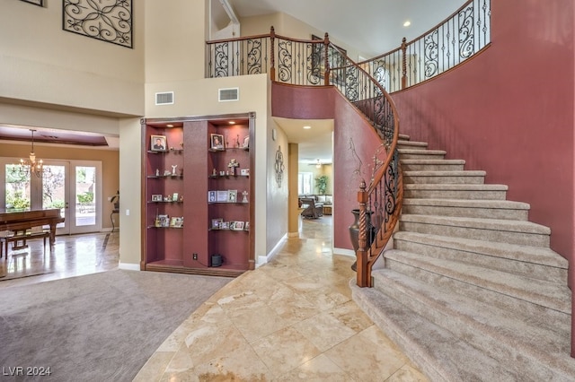 entryway featuring a notable chandelier, a towering ceiling, carpet, and french doors