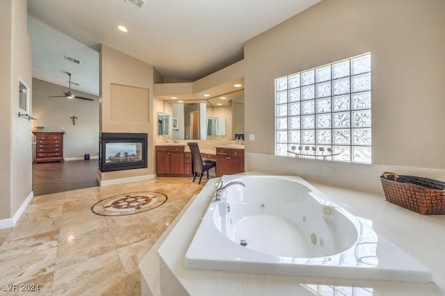 bathroom featuring lofted ceiling, ceiling fan, vanity, tiled bath, and a multi sided fireplace