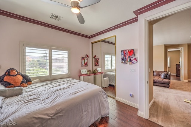 bedroom featuring a closet, hardwood / wood-style floors, ornamental molding, and ceiling fan