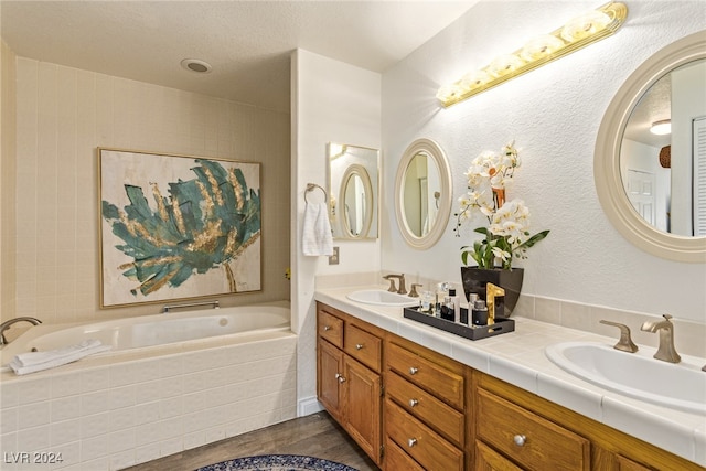 bathroom with tiled tub, vanity, and hardwood / wood-style flooring