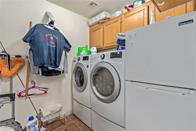 laundry area featuring dark tile patterned floors, separate washer and dryer, and cabinets