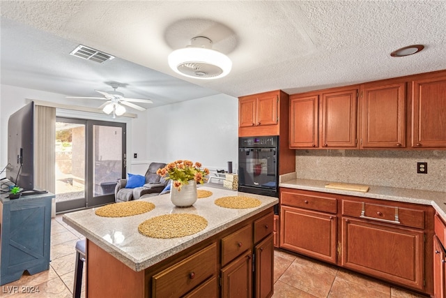 kitchen featuring a center island, oven, and a textured ceiling