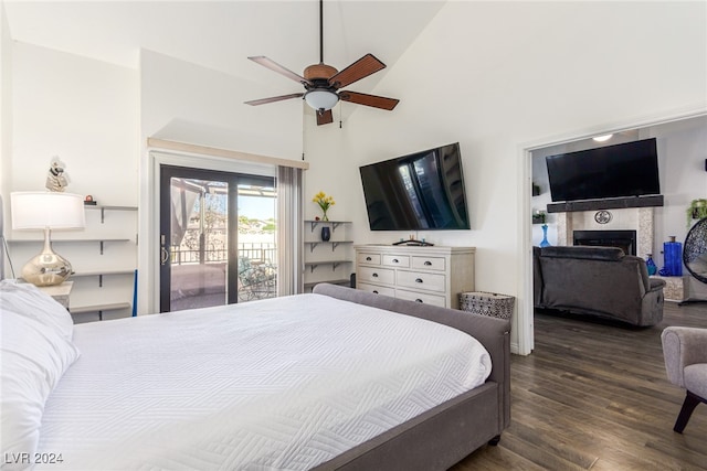 bedroom with high vaulted ceiling, ceiling fan, dark wood-type flooring, a tiled fireplace, and access to exterior