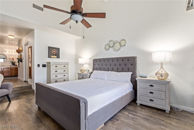 bedroom with ceiling fan, ensuite bath, and dark hardwood / wood-style flooring