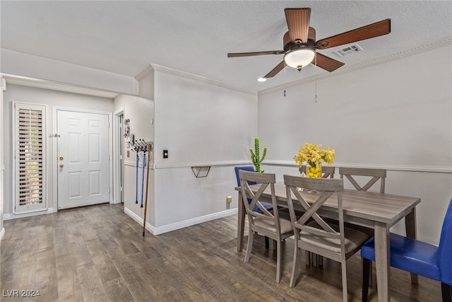 dining area with dark wood-type flooring, ornamental molding, a textured ceiling, and ceiling fan