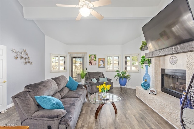 living room featuring plenty of natural light, dark hardwood / wood-style floors, a tiled fireplace, and lofted ceiling with beams