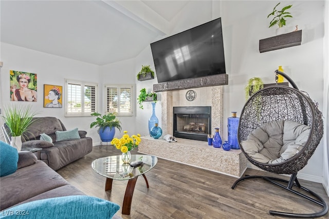 living room with vaulted ceiling with beams, hardwood / wood-style floors, and a tile fireplace