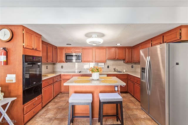 kitchen with a kitchen island, black appliances, tasteful backsplash, sink, and a breakfast bar area