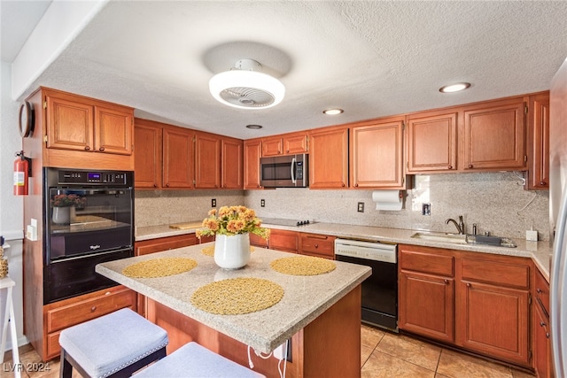 kitchen with sink, a kitchen island, black appliances, a kitchen breakfast bar, and light stone countertops