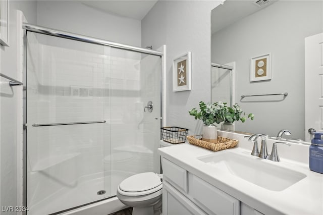 bathroom featuring vanity, toilet, and a shower with shower door