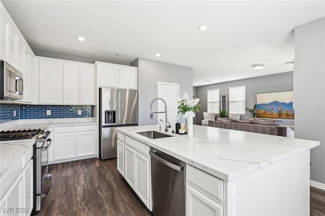 kitchen featuring sink, a center island with sink, appliances with stainless steel finishes, dark hardwood / wood-style floors, and light stone countertops