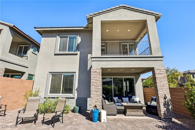 back of property with a patio, a balcony, and an outdoor living space with a fire pit