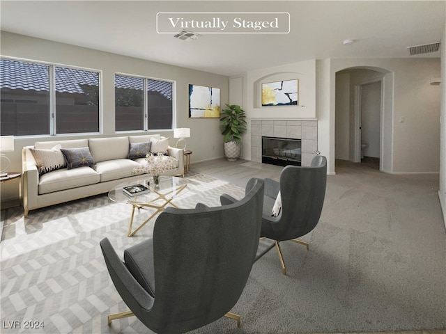 carpeted living room featuring a tiled fireplace