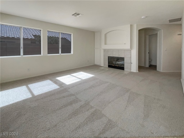 unfurnished living room with light colored carpet and a tile fireplace