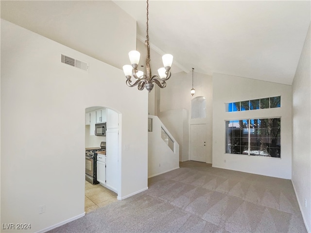 carpeted spare room with high vaulted ceiling and a chandelier