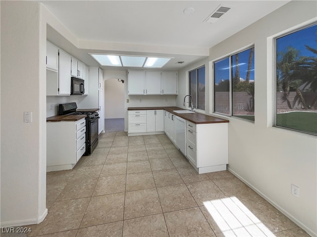 kitchen featuring white cabinets, black appliances, light tile patterned floors, and sink