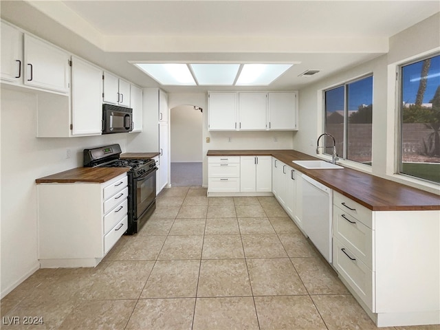 kitchen featuring white cabinets, sink, wooden counters, and black appliances