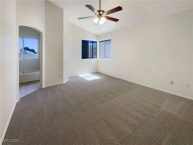 carpeted spare room featuring ceiling fan, lofted ceiling, and a wealth of natural light