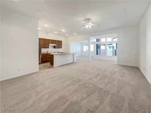 unfurnished living room featuring light carpet, ceiling fan, and sink