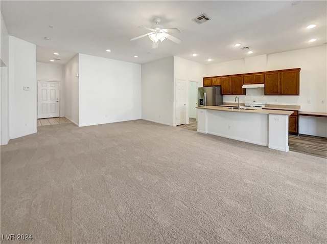 kitchen with a kitchen island with sink, stainless steel refrigerator with ice dispenser, light colored carpet, white range oven, and ceiling fan