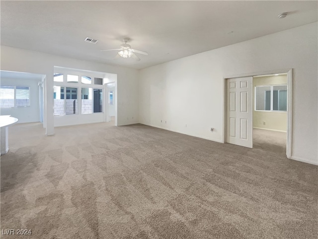 unfurnished living room featuring ceiling fan and light carpet