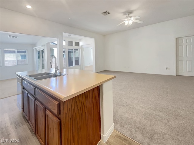 kitchen featuring white dishwasher, ceiling fan, a center island with sink, sink, and light carpet