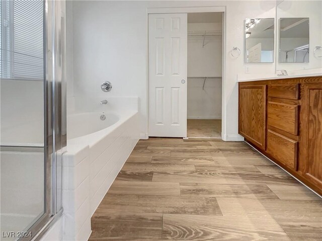 bathroom with shower with separate bathtub, vanity, and wood-type flooring