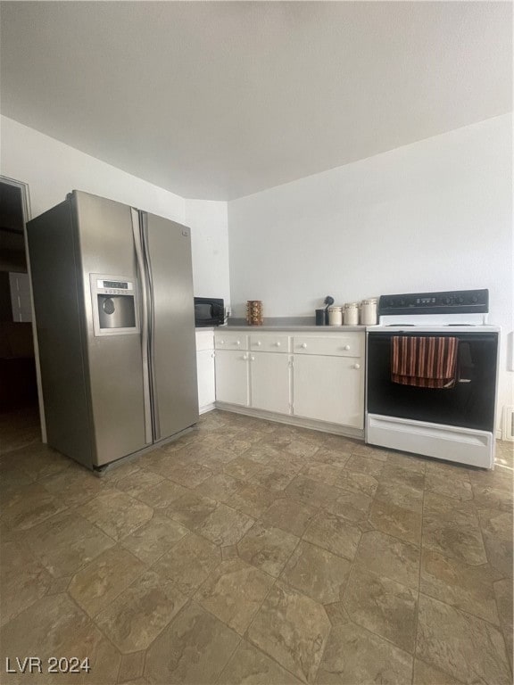 kitchen featuring white cabinets, stainless steel fridge, and white range oven