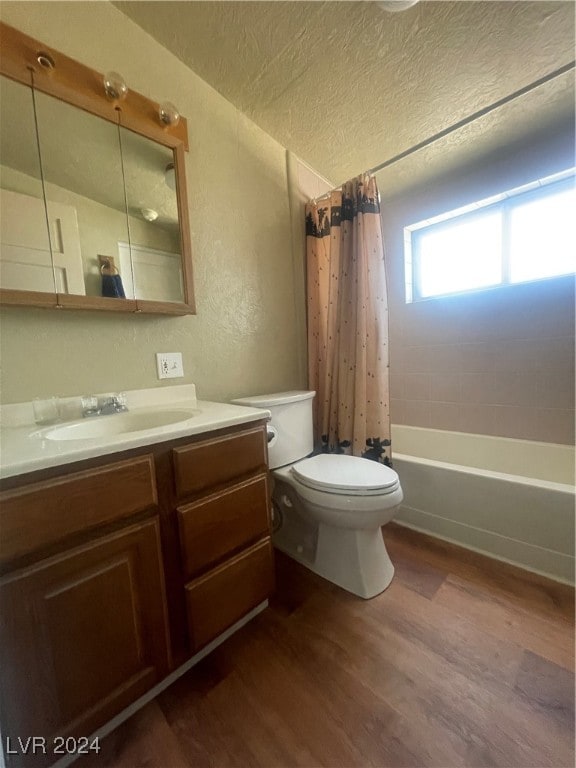 full bathroom with vanity, wood-type flooring, a textured ceiling, shower / bathtub combination with curtain, and toilet