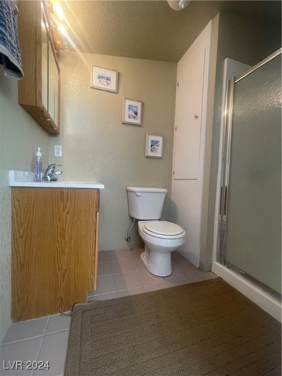 bathroom featuring vanity, a textured ceiling, a shower with shower door, tile patterned floors, and toilet