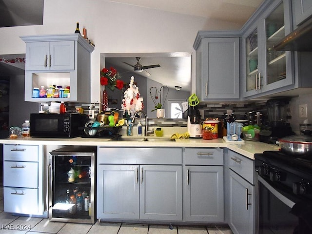 kitchen featuring black appliances, lofted ceiling, tasteful backsplash, wine cooler, and sink