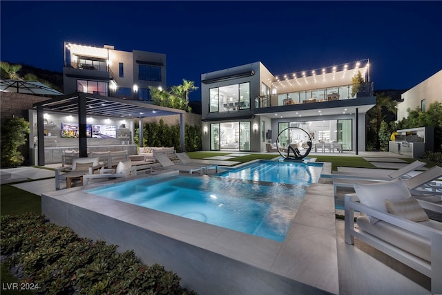 pool at night with outdoor lounge area, a patio, and an in ground hot tub