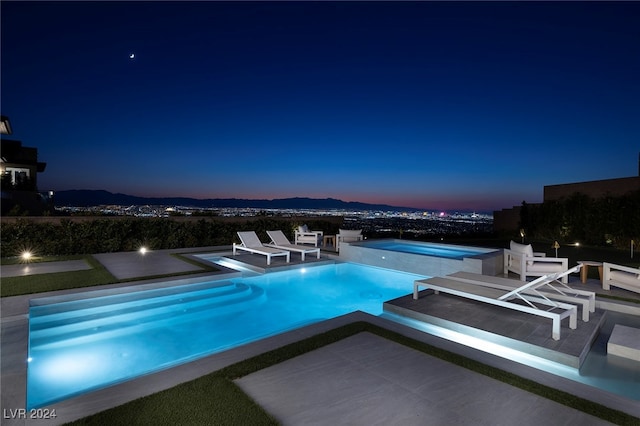 pool at dusk with a mountain view and a patio area