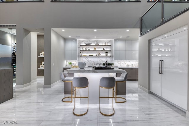 kitchen with white cabinetry, built in refrigerator, a kitchen island, a kitchen breakfast bar, and backsplash