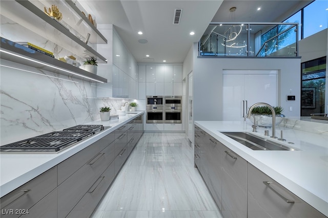 kitchen featuring hanging light fixtures, sink, gray cabinetry, appliances with stainless steel finishes, and decorative backsplash