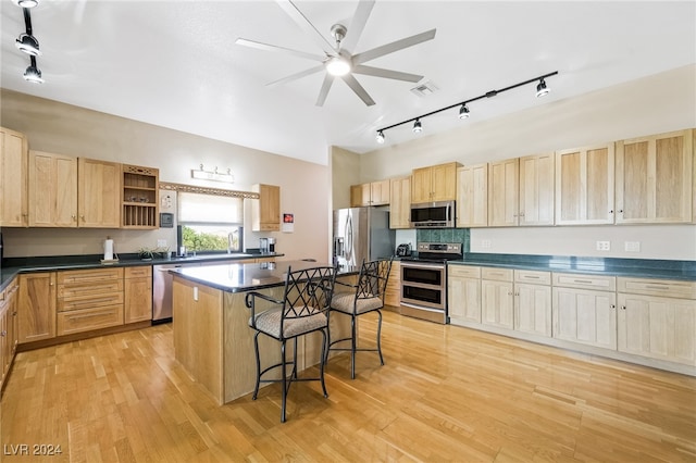 kitchen with a kitchen island, light hardwood / wood-style flooring, stainless steel appliances, a kitchen breakfast bar, and ceiling fan