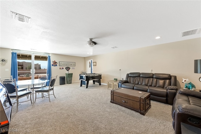 living room featuring a textured ceiling, ceiling fan, and light colored carpet