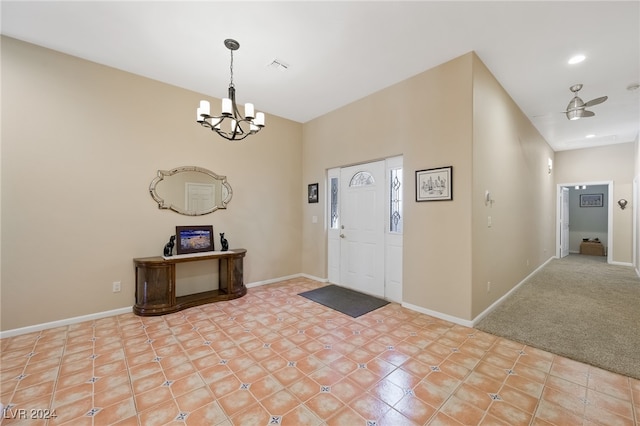 entrance foyer featuring ceiling fan with notable chandelier and light carpet