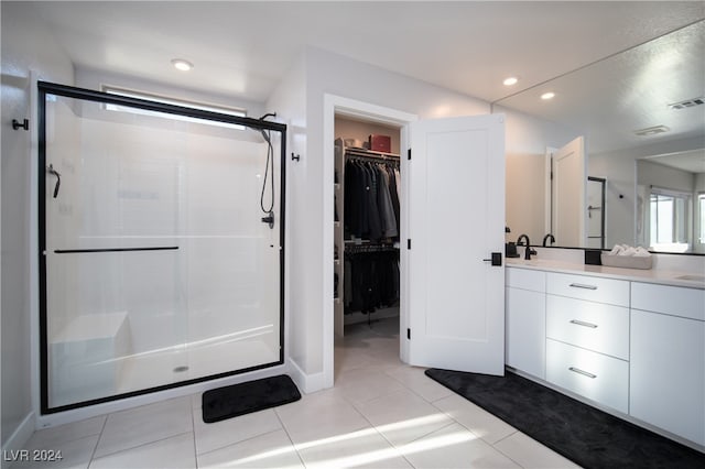 bathroom with tile patterned flooring, walk in shower, and vanity