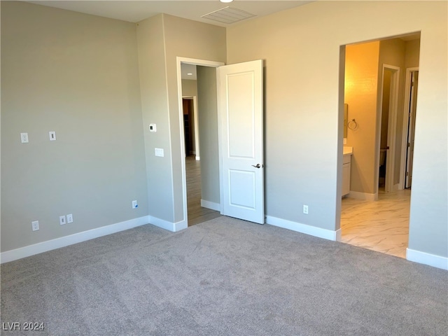 unfurnished bedroom with light carpet and ensuite bath