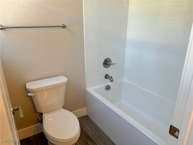 bathroom with hardwood / wood-style floors, tiled shower / bath combo, and toilet