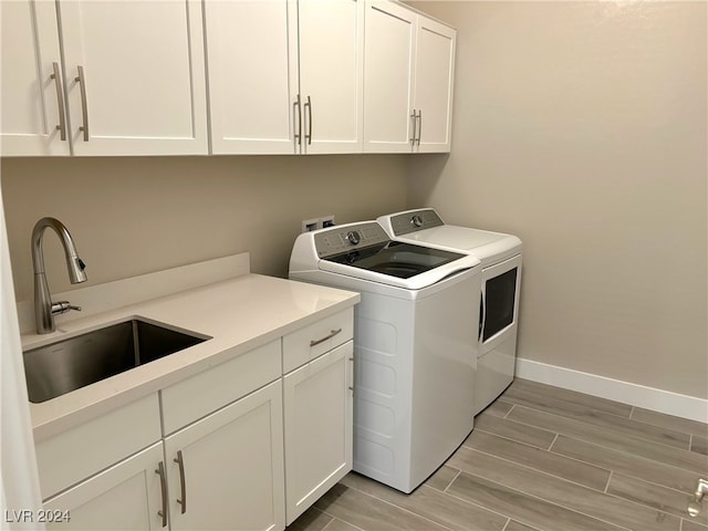 laundry area with cabinets, light wood-type flooring, separate washer and dryer, and sink