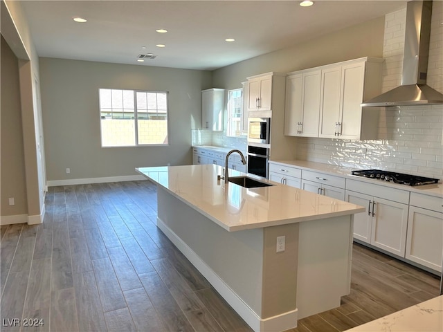 kitchen featuring a kitchen island with sink, sink, wall chimney exhaust hood, and hardwood / wood-style flooring