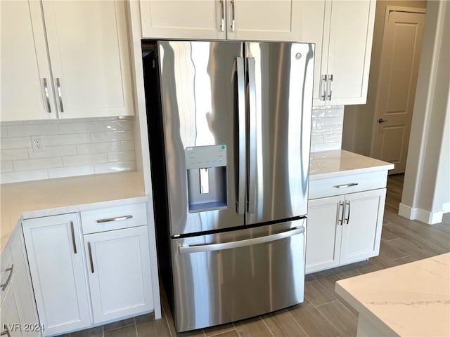 kitchen featuring light stone countertops, stainless steel refrigerator with ice dispenser, decorative backsplash, white cabinets, and hardwood / wood-style flooring