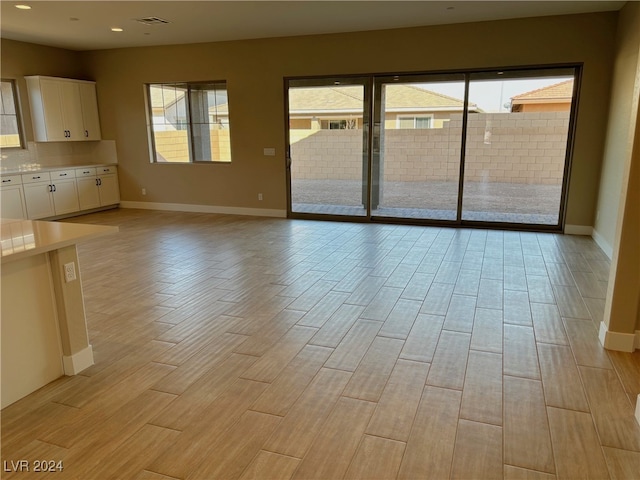 unfurnished living room with light wood-type flooring and a wealth of natural light